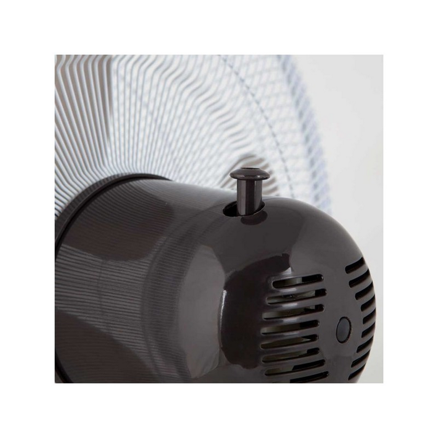 Primer plano del motor de un ventilador marrón oscuro, con diseño circular y un botón pequeño.
