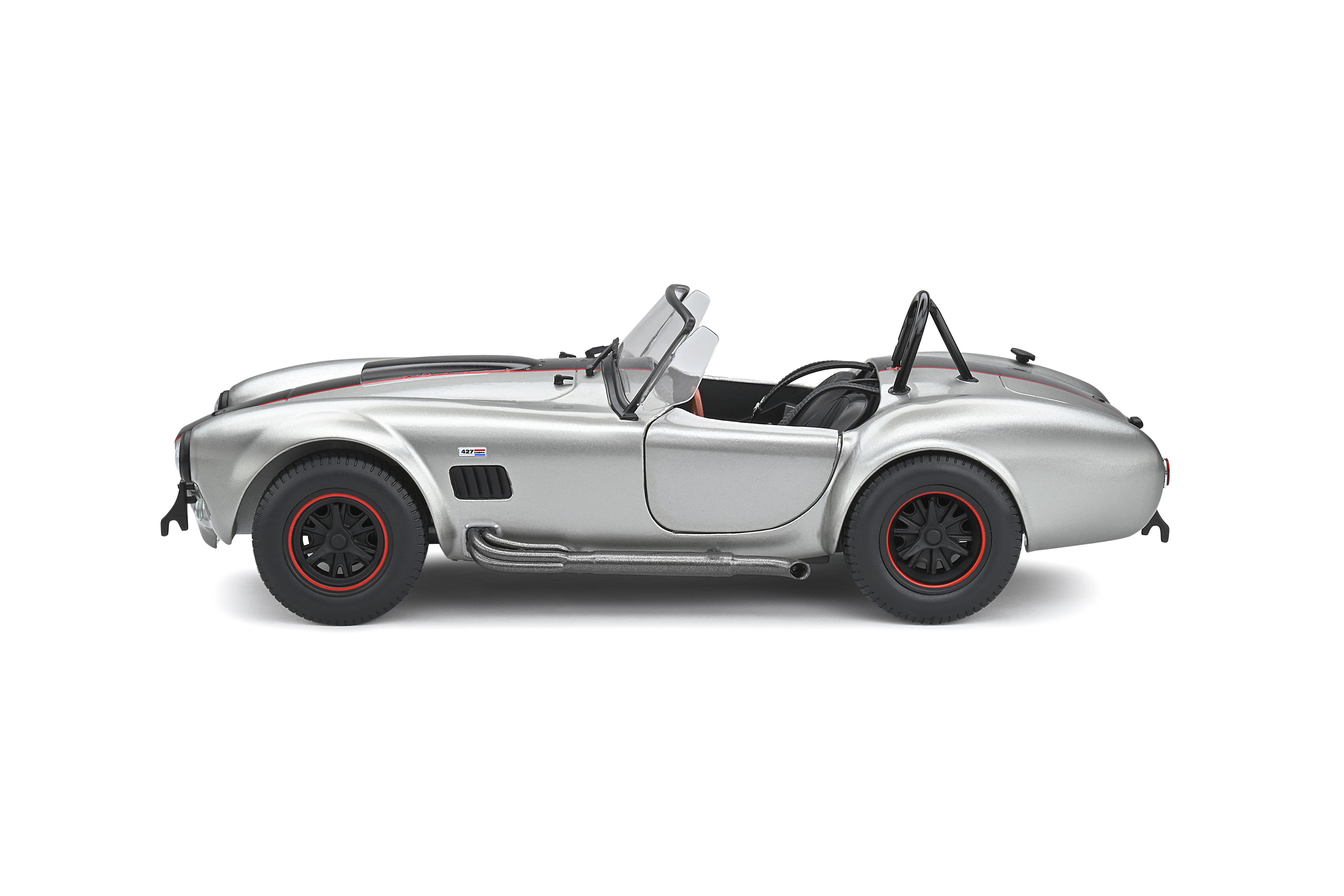 Silbernes Oldtimer-Auto von der Seite. Es hat schwarze Räder und einen roten Streifen.