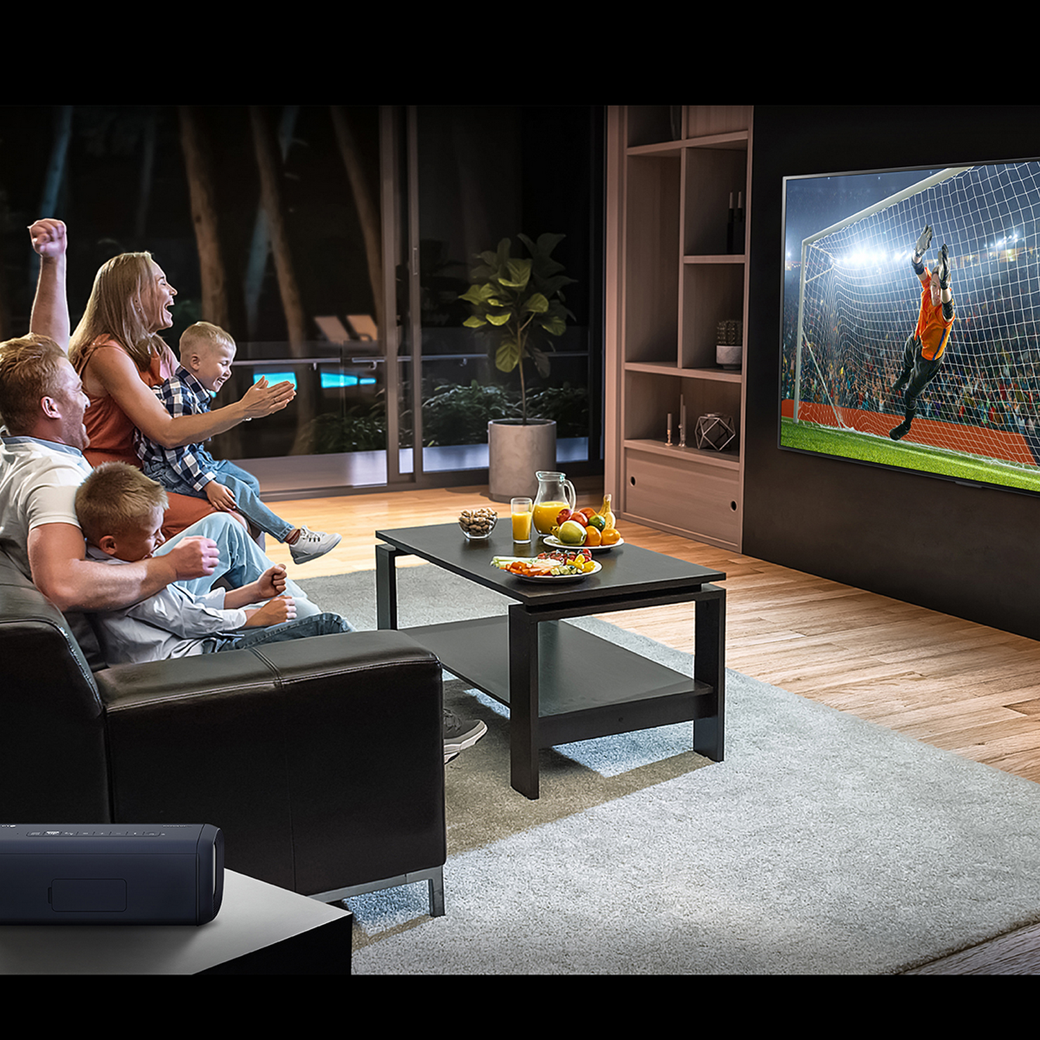 Familia viendo fútbol en la tele. Celebran un gol. Ambiente de salón.