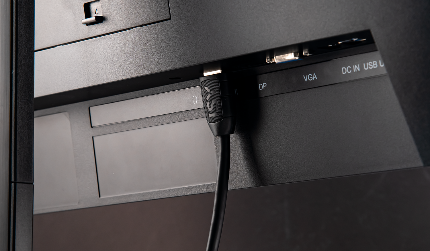Back of a monitor with ports. A black cable is plugged into the monitor.