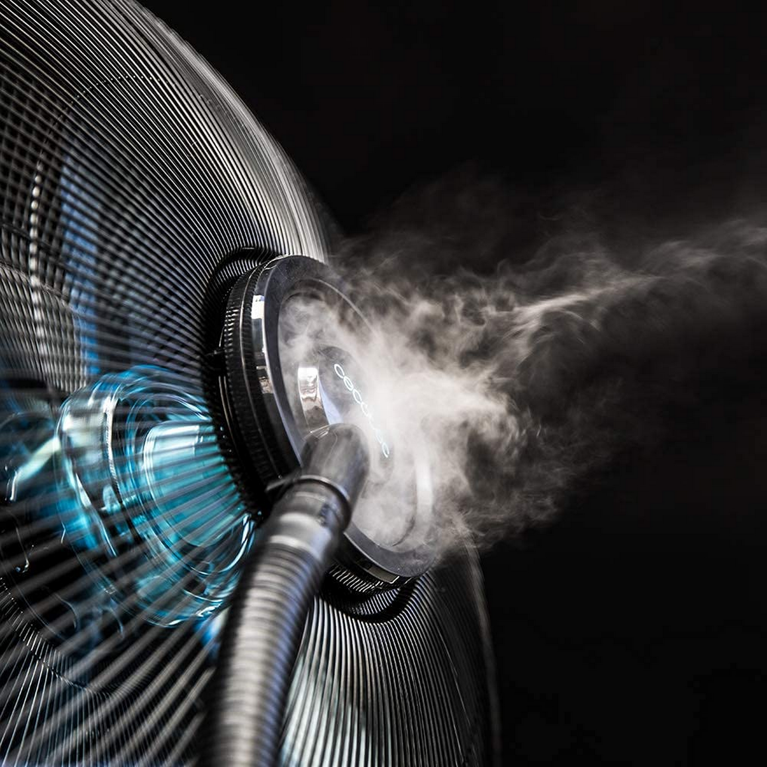 Un ventilador rociando niebla, con luces azules y un fondo oscuro.