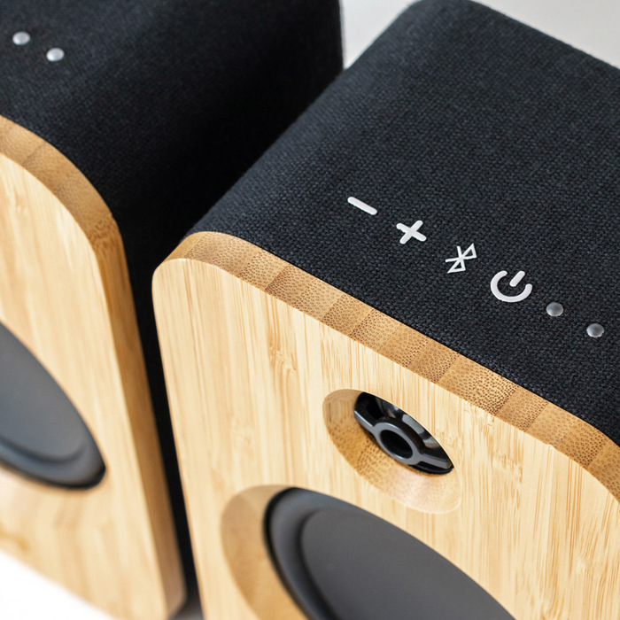 Deux enceintes en bois avec façades en tissu. Boutons de commande sur le dessus.