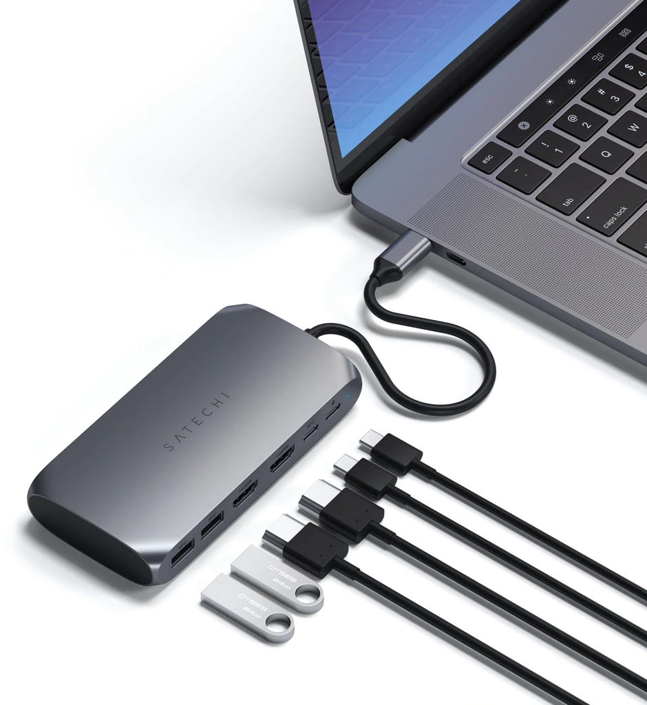 Un hub argentato collegato a un laptop con USB e alcune unità USB.