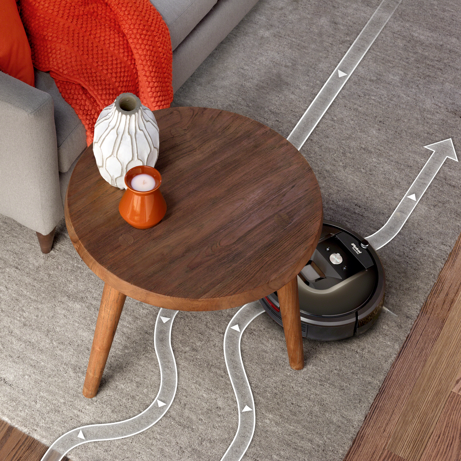 Robot aspirador limpiando una alfombra. Una mesa de madera y jarrones están en la alfombra. Flechas muestran la ruta.
