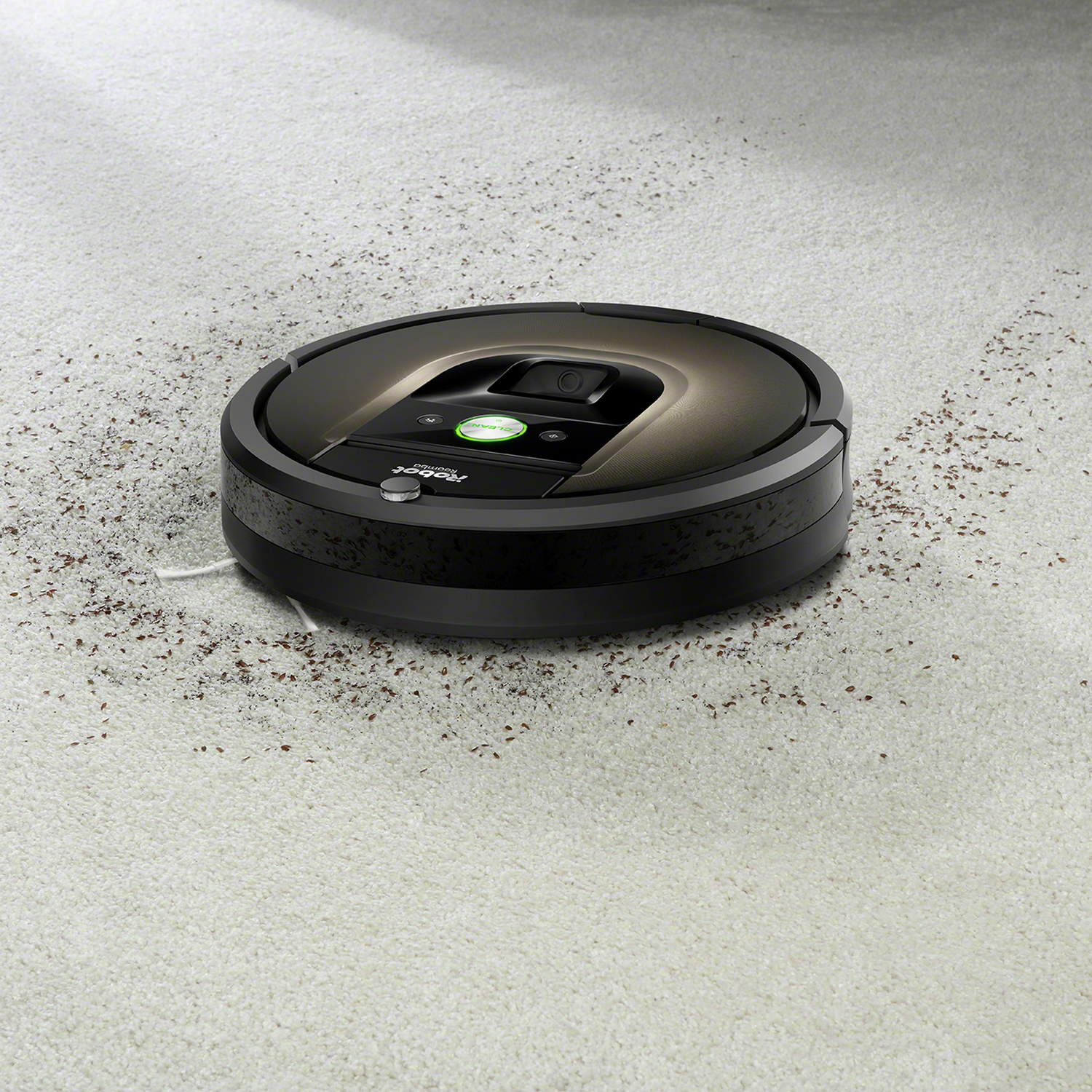 Una aspiradora robot negra y gris sobre una alfombra de color claro.