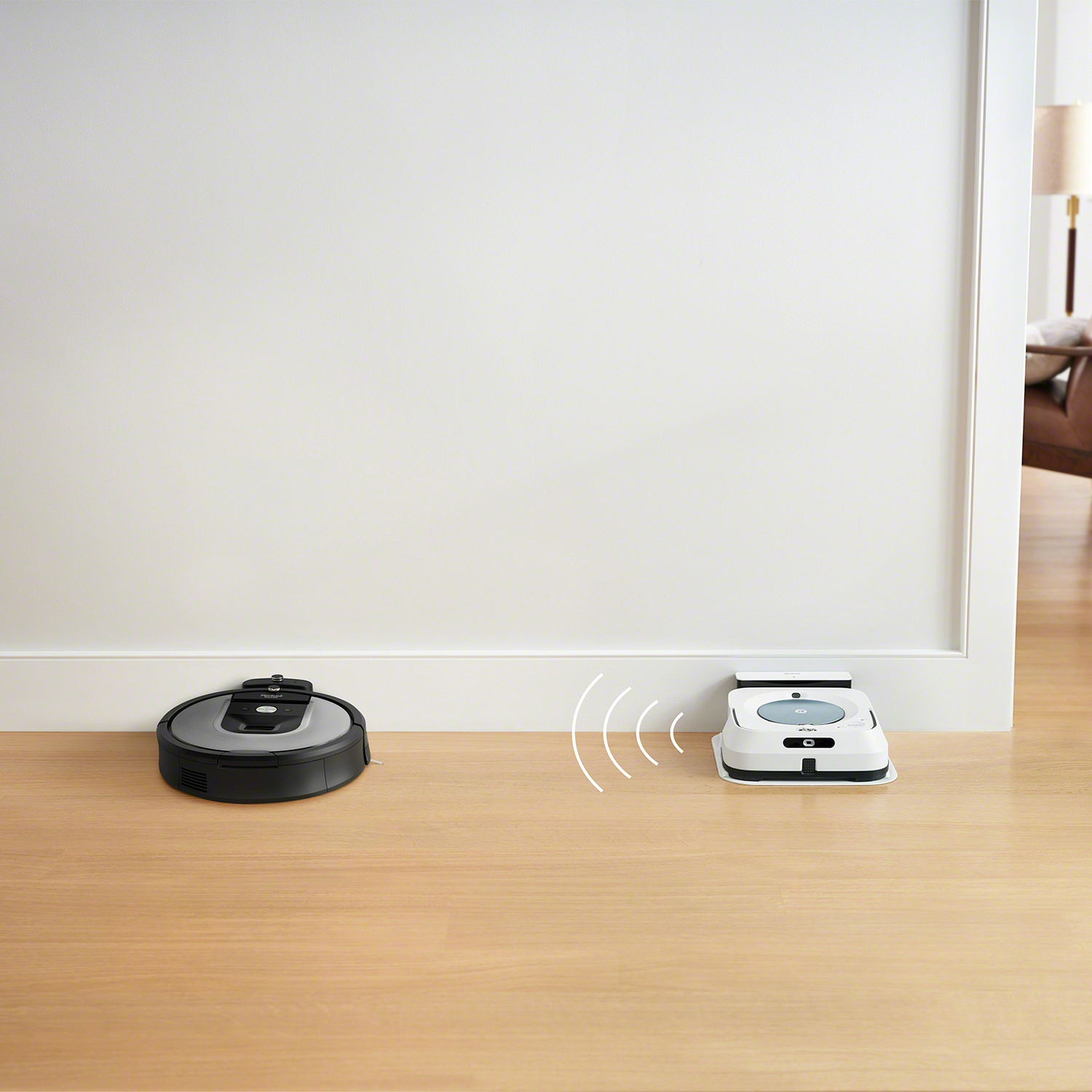Aspiradora robot y estación base en piso de madera; líneas blancas indican la ruta de limpieza.