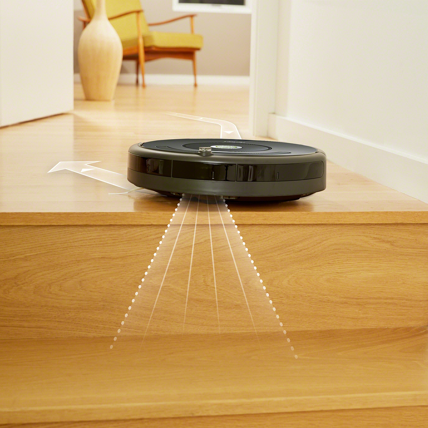 Un robot aspirador negro en un escalón de madera con flechas.