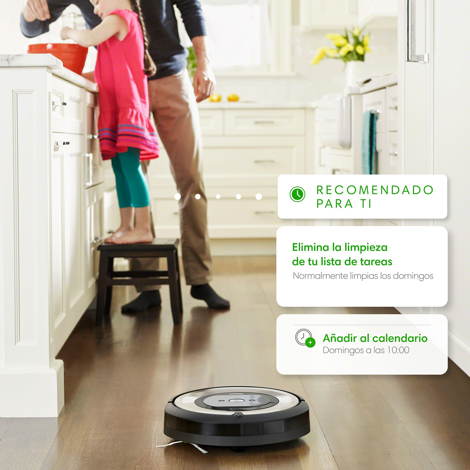 Un robot aspirador limpiando un suelo de madera. Dos personas en el fondo, en una cocina.