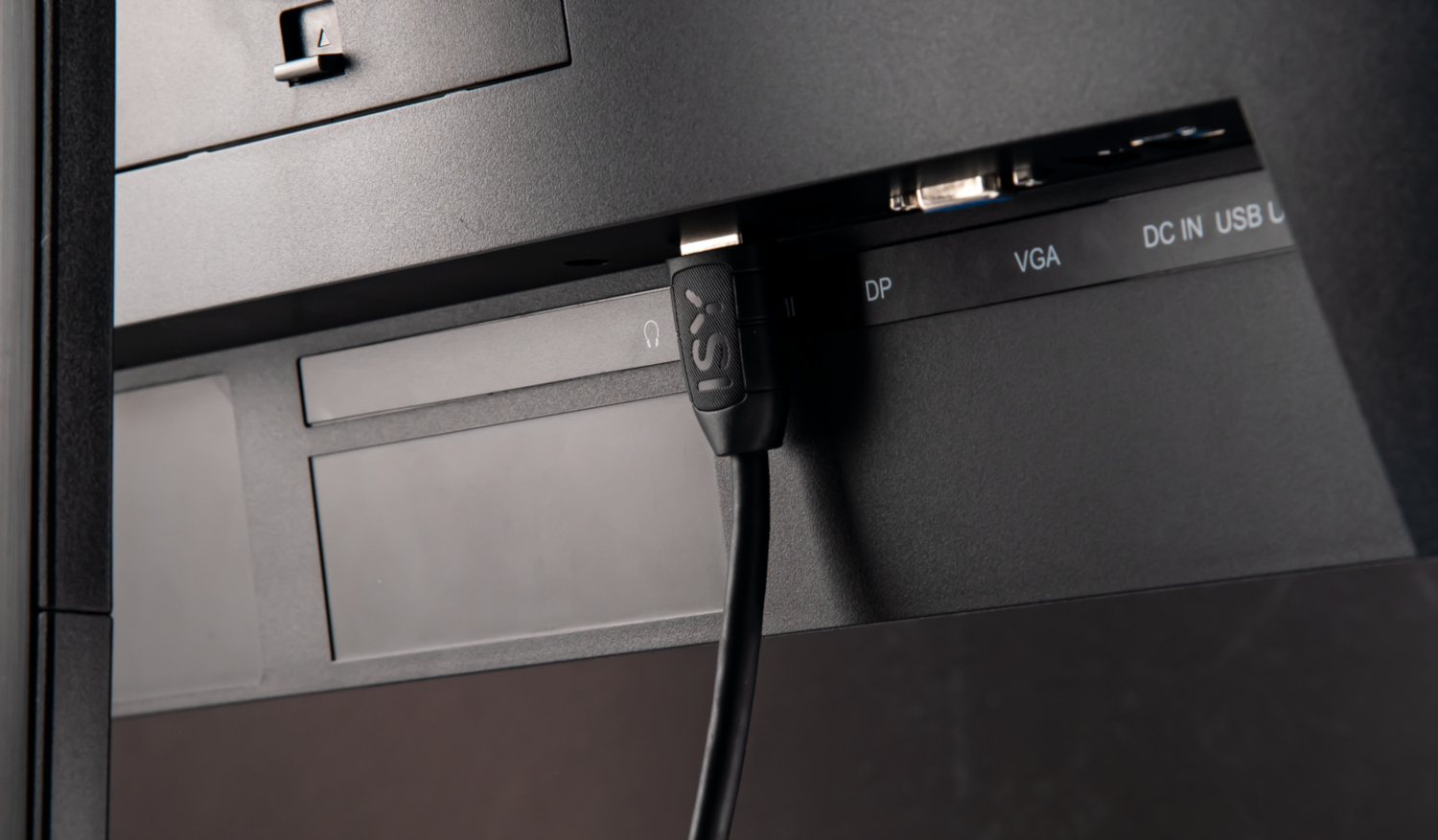 Close-up van de achterkant van een monitor met poorten en een zwarte HDMI-kabel.