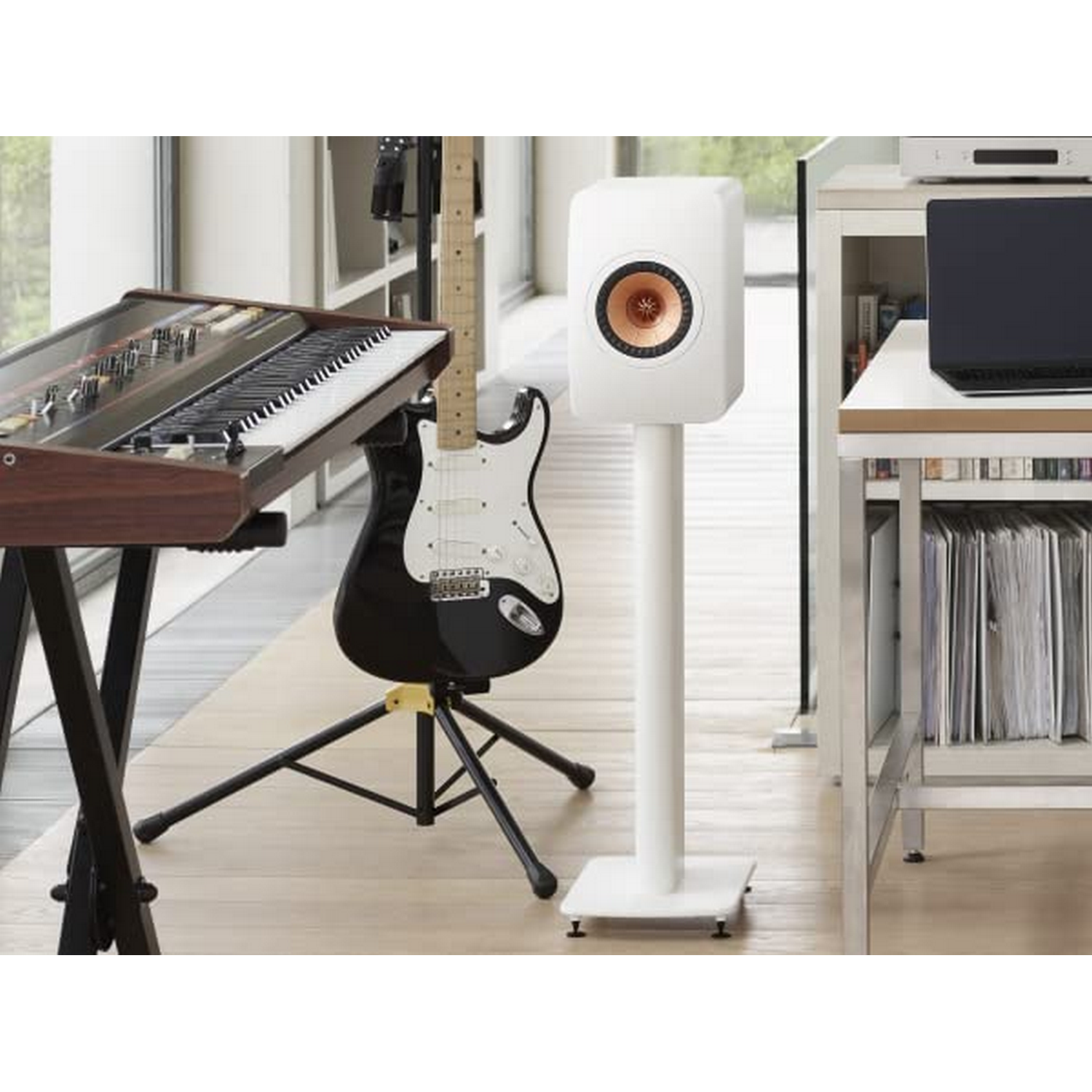 Habitación con teclado, guitarra, altavoz y portátil en soporte blanco.