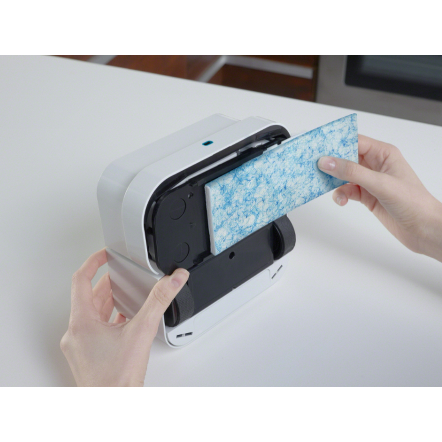 Manos insertando un filtro en un dispositivo de limpieza blanco y gris.
