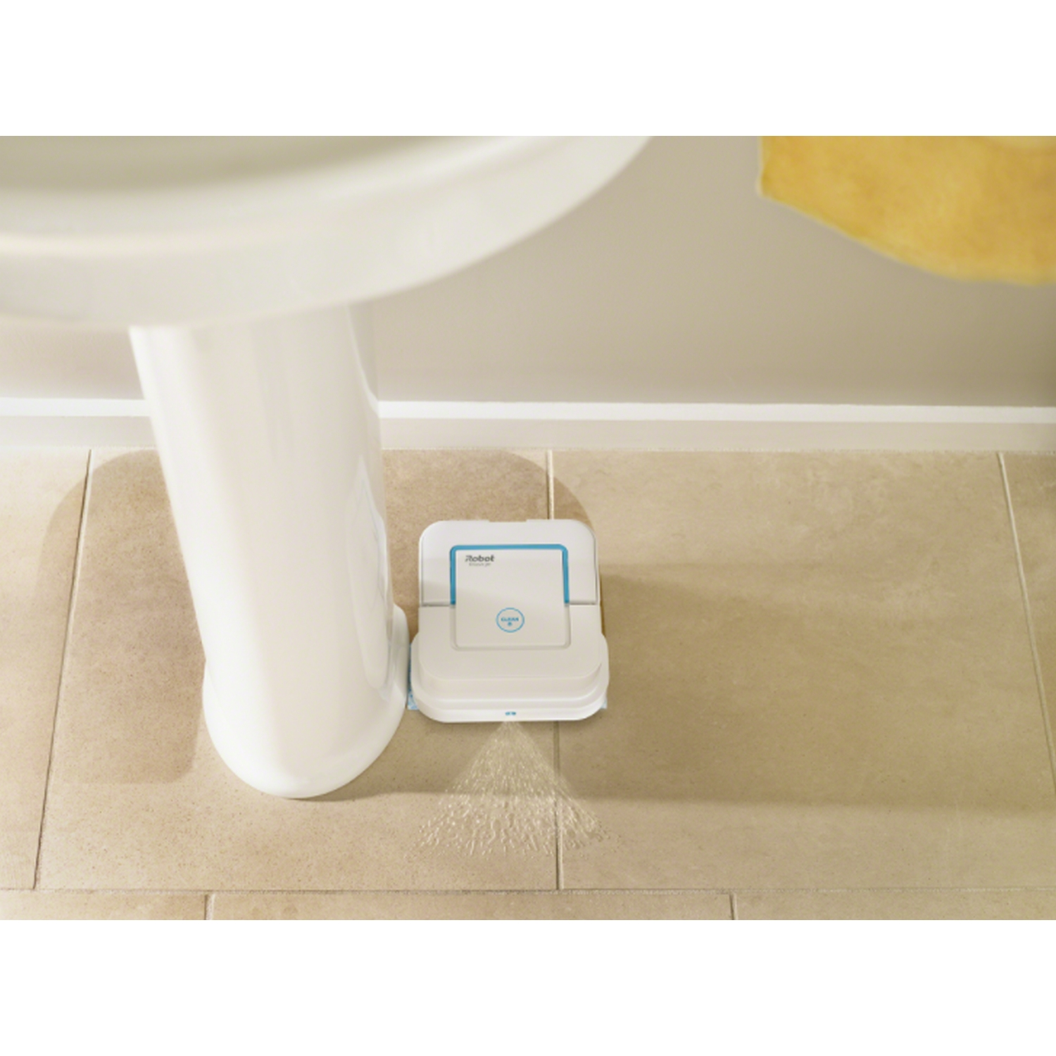 Limpiador robot blanco limpiando piso embaldosado cerca de un lavabo blanco.