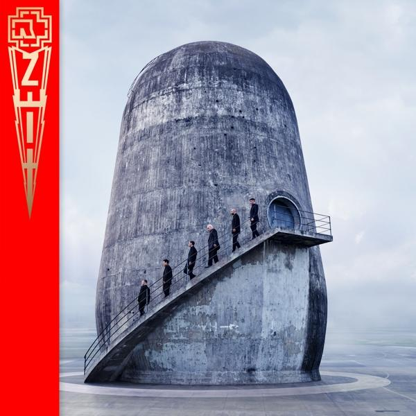 Betongebäude mit Personen auf Treppen, Rammstein-Logo links und ZHI auf dem Gebäude.