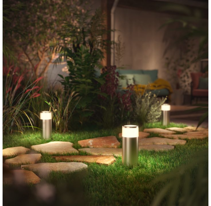 Garden scene with three silver outdoor lights illuminating a stone path.