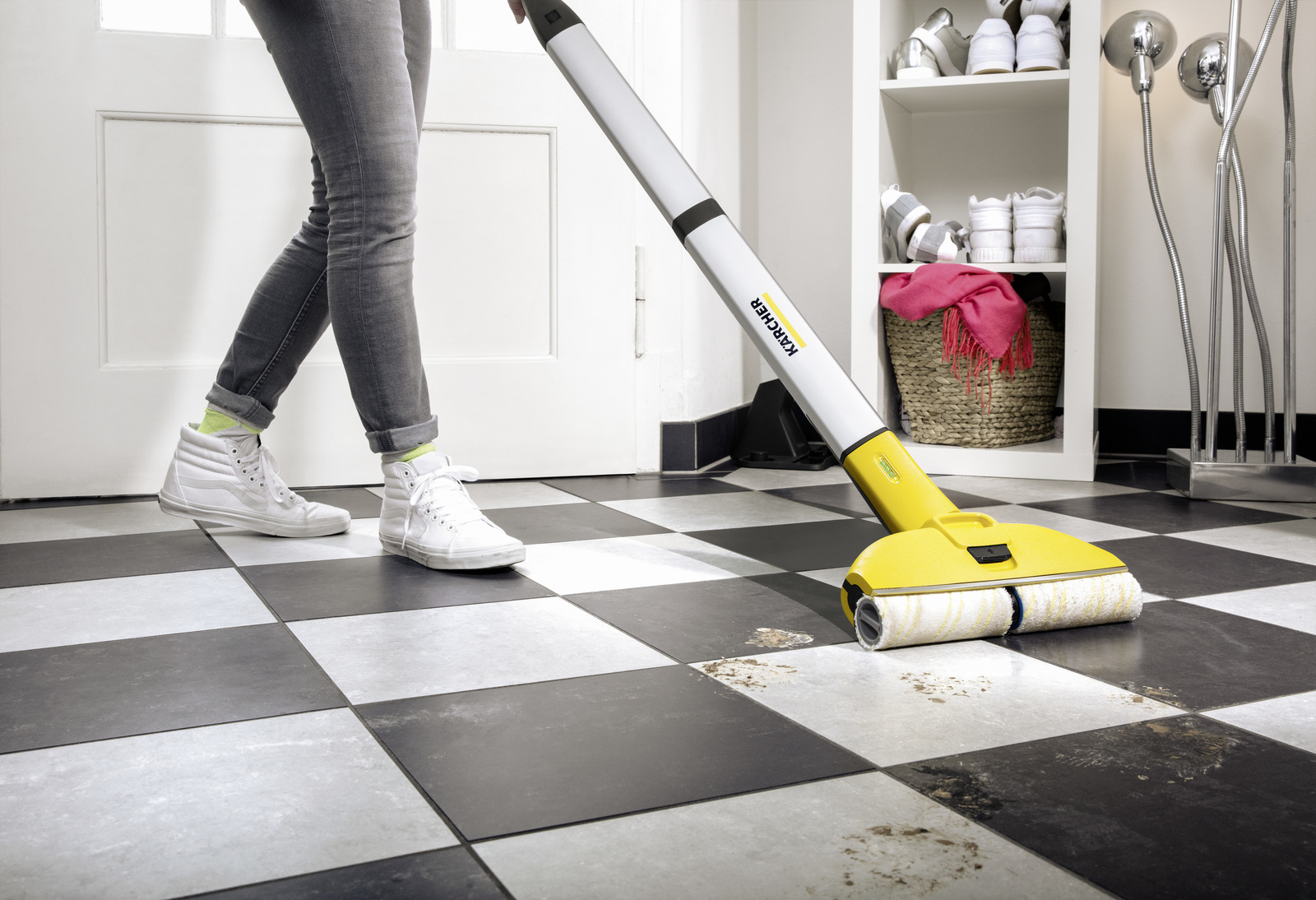 Vrouw maakt een geblokte vloer schoon met een Kärcher vloerreiniger. Vuil is zichtbaar op de vloer.