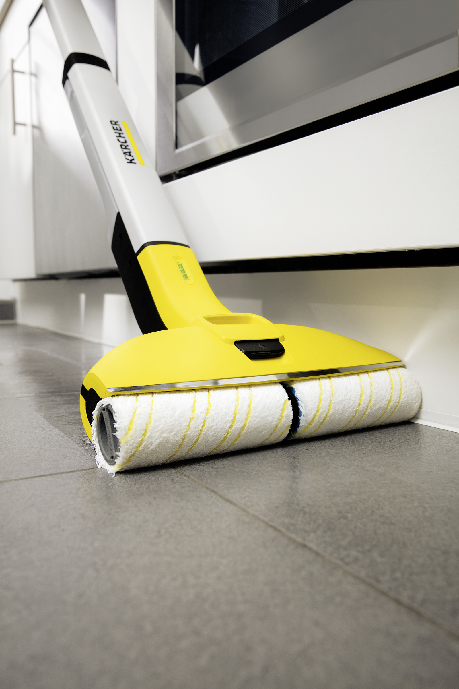 Een gele Kärcher-vloerreiniger maakt een vloer schoon.