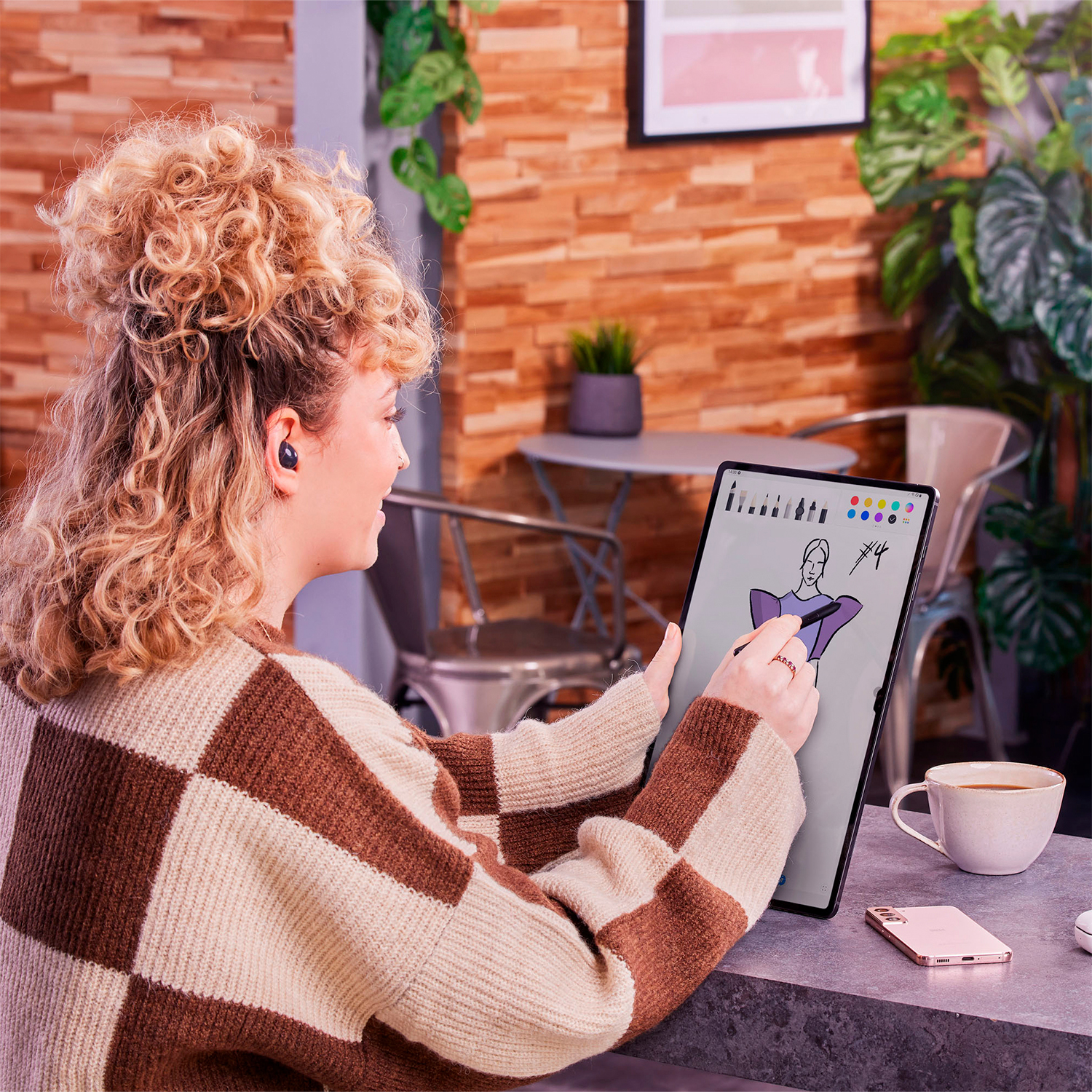Mujer usando una tableta con lápiz, dibujando en un café.