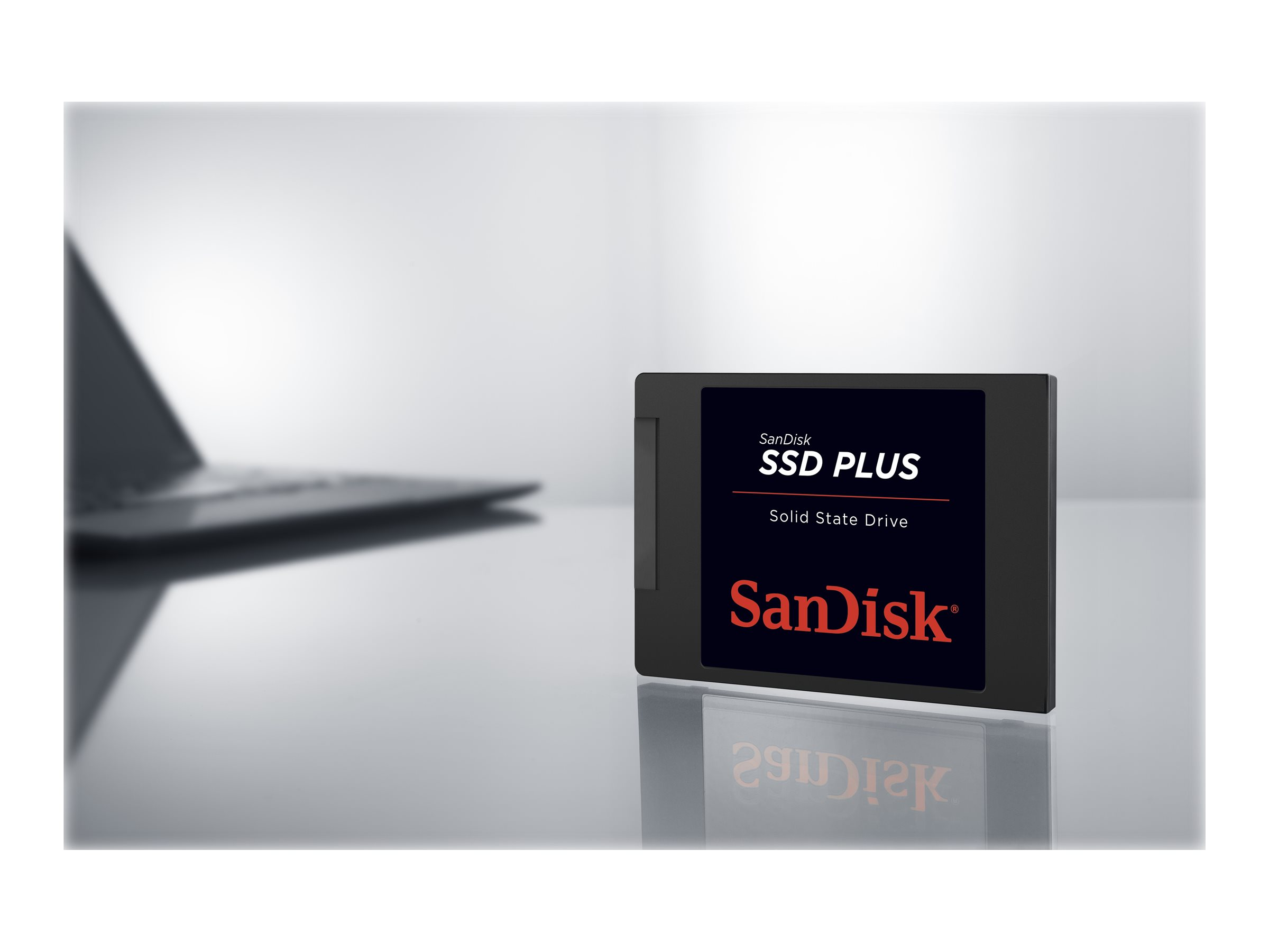 Schwarze SSD-Festplatte und ein Laptop auf reflektierender Oberfläche.