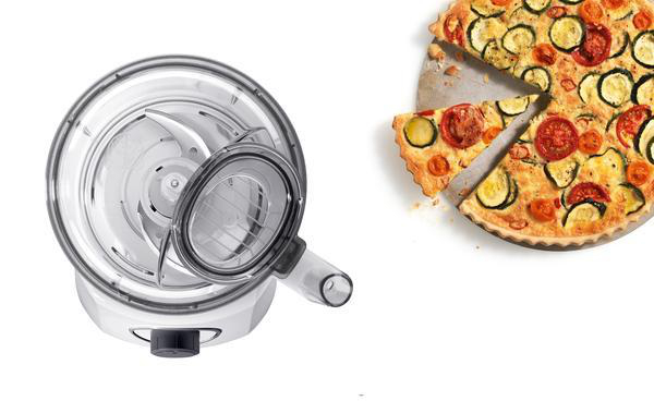 Küchenmaschine und geschnittener Quiche mit Tomaten und Zucchini auf weißem Hintergrund.