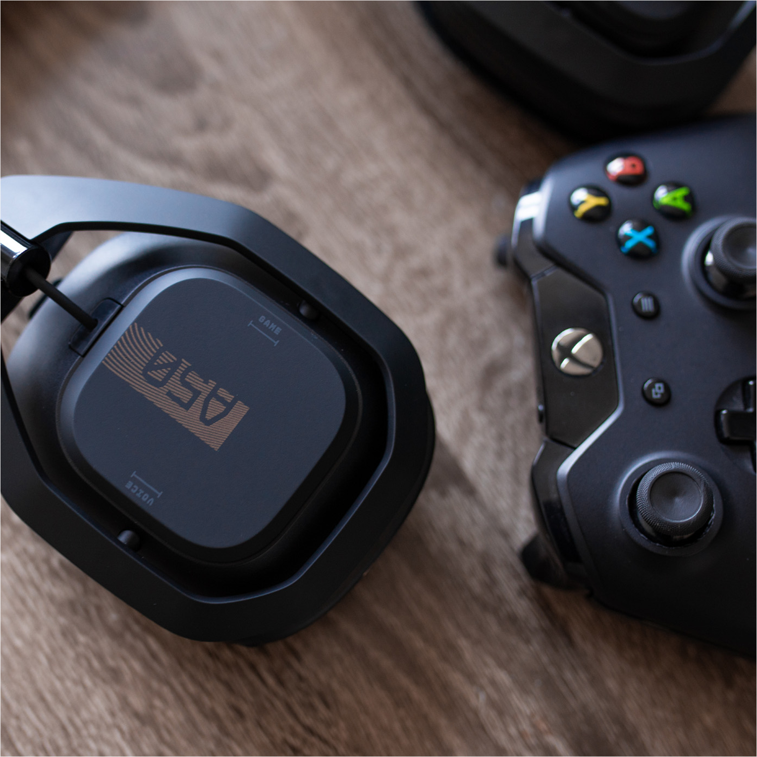 Casque de jeu noir et une manette de jeu noire sur une surface en bois.
