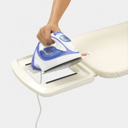 A hand holding a blue and white iron over an ironing board. The board has a small tray.