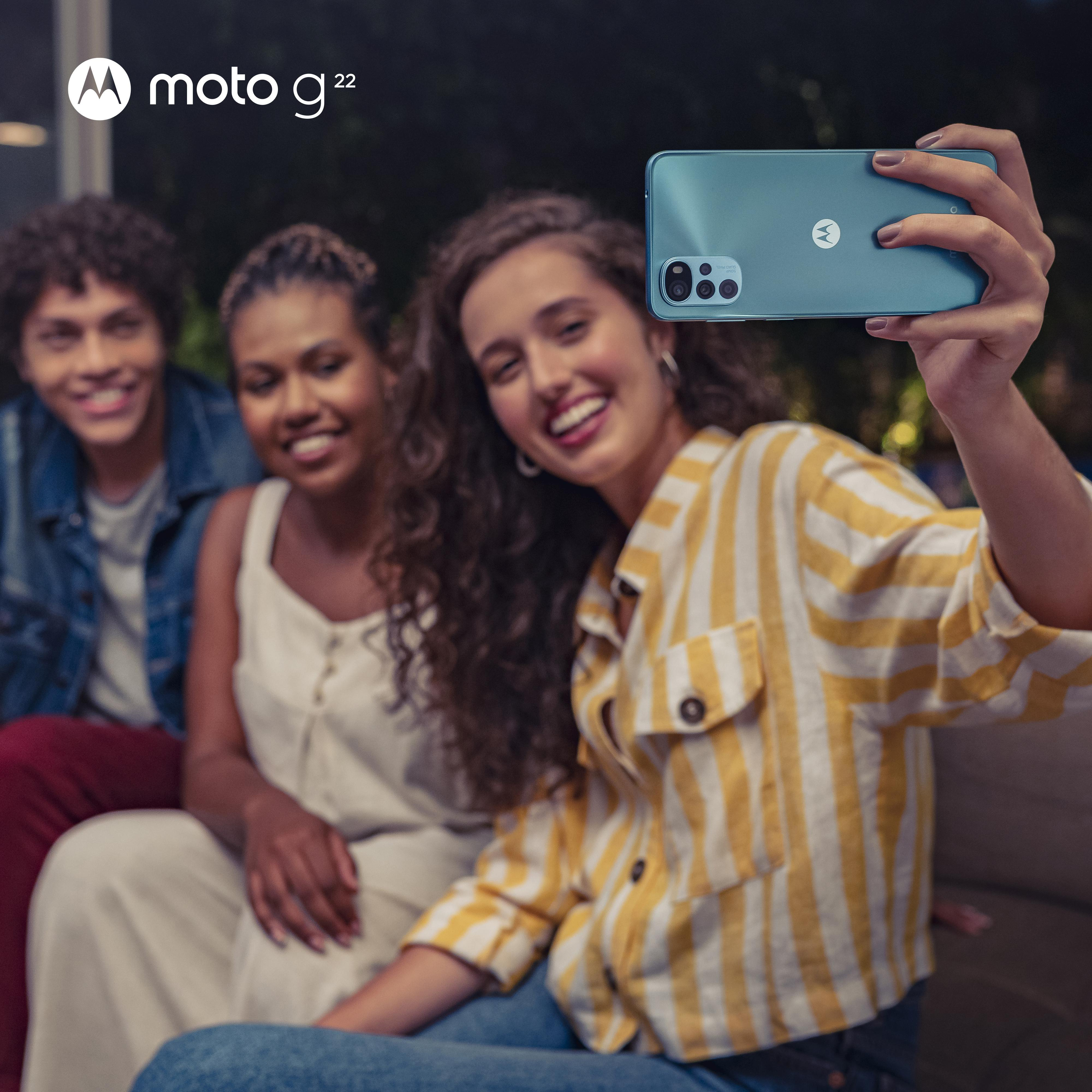 Drei Personen machen ein Selfie mit einem türkisfarbenen Telefon. Sie lächeln und sind draußen.