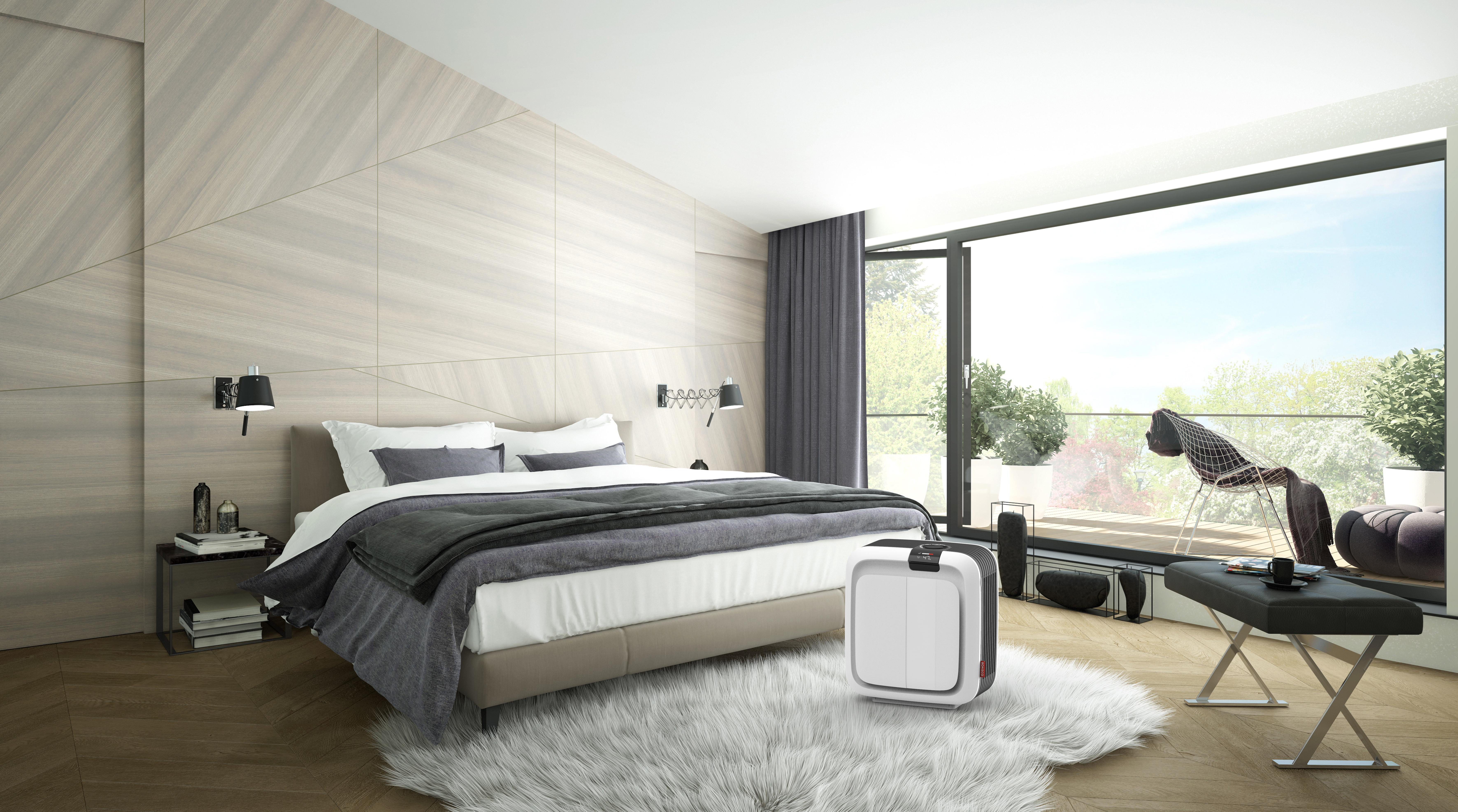 Schlafzimmer-Szene mit Bett, Fenster und einem Luftreiniger auf einem flauschigen Teppich.