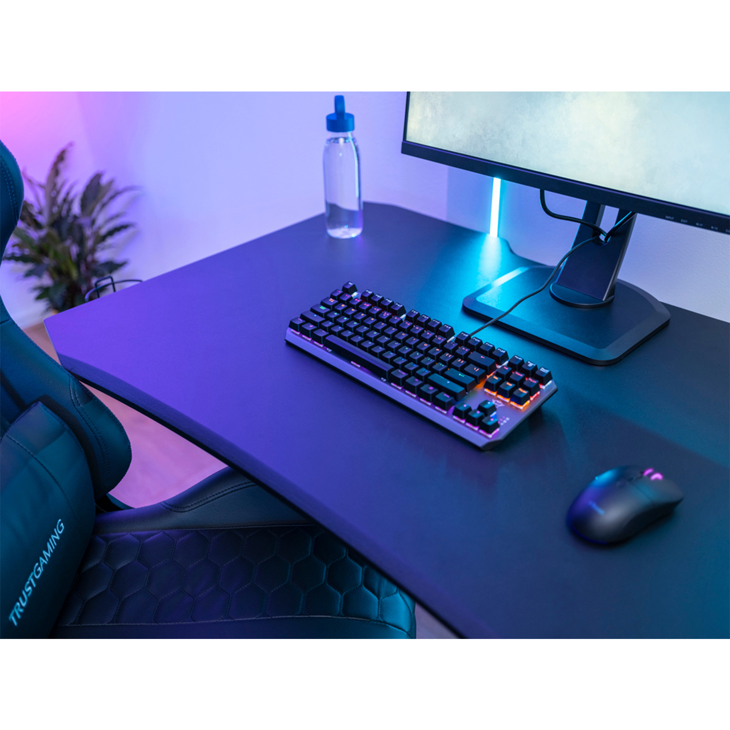 Configurazione di gioco con tastiera, mouse, monitor, sedia e bottiglia d'acqua.