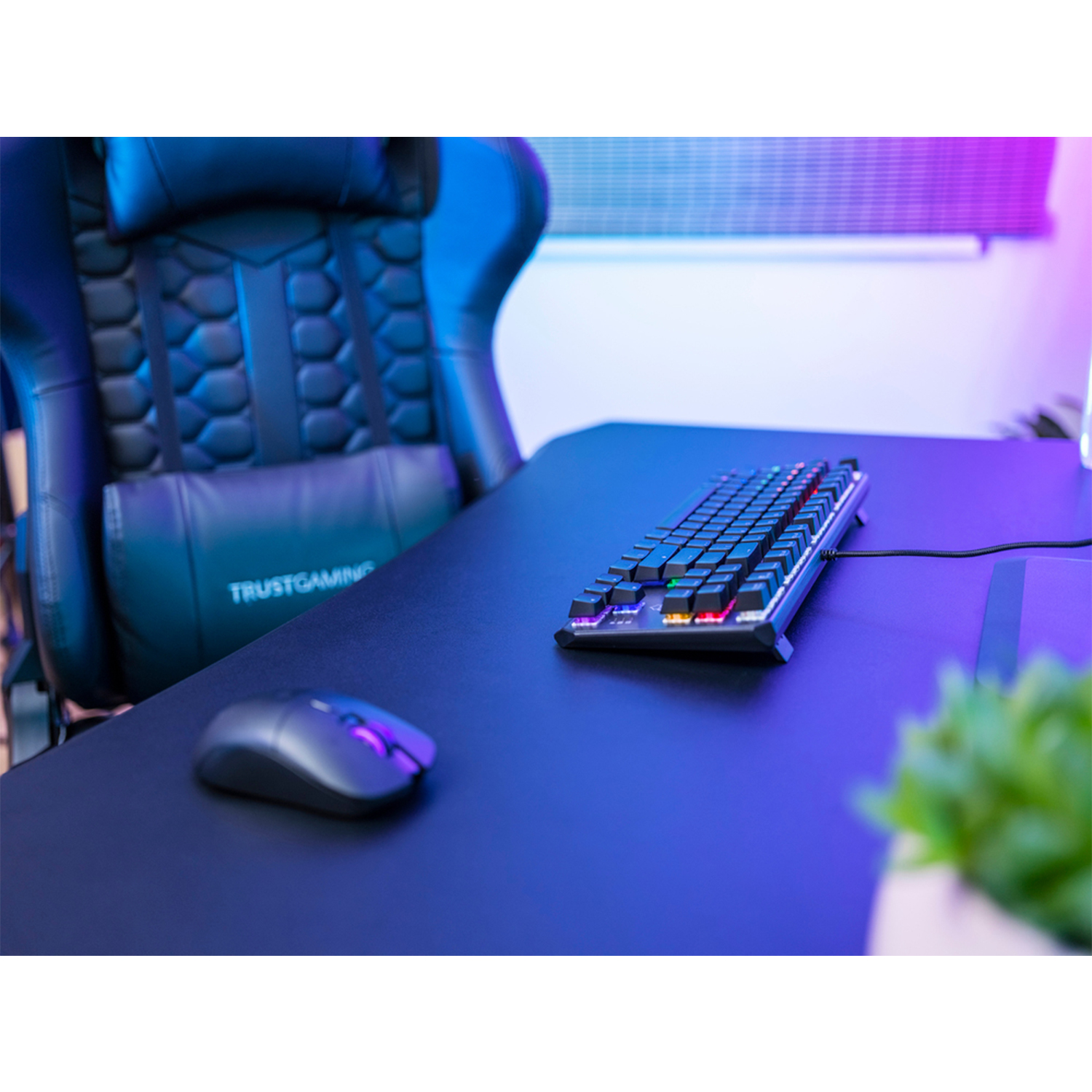 Configurazione gaming: tastiera, mouse e sedia gaming su una scrivania nera con luci al neon.
