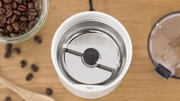 Das Innere einer Kaffeemühle mit Kaffeebohnen drumherum.