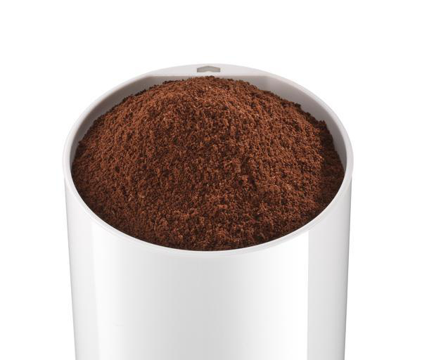 Nahaufnahme einer weißen Kaffeemühle, gefüllt mit gemahlenen Kaffeebohnen.