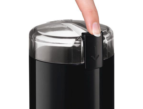 Finger drückt schwarzen Knopf auf schwarzer Kaffeemühle.