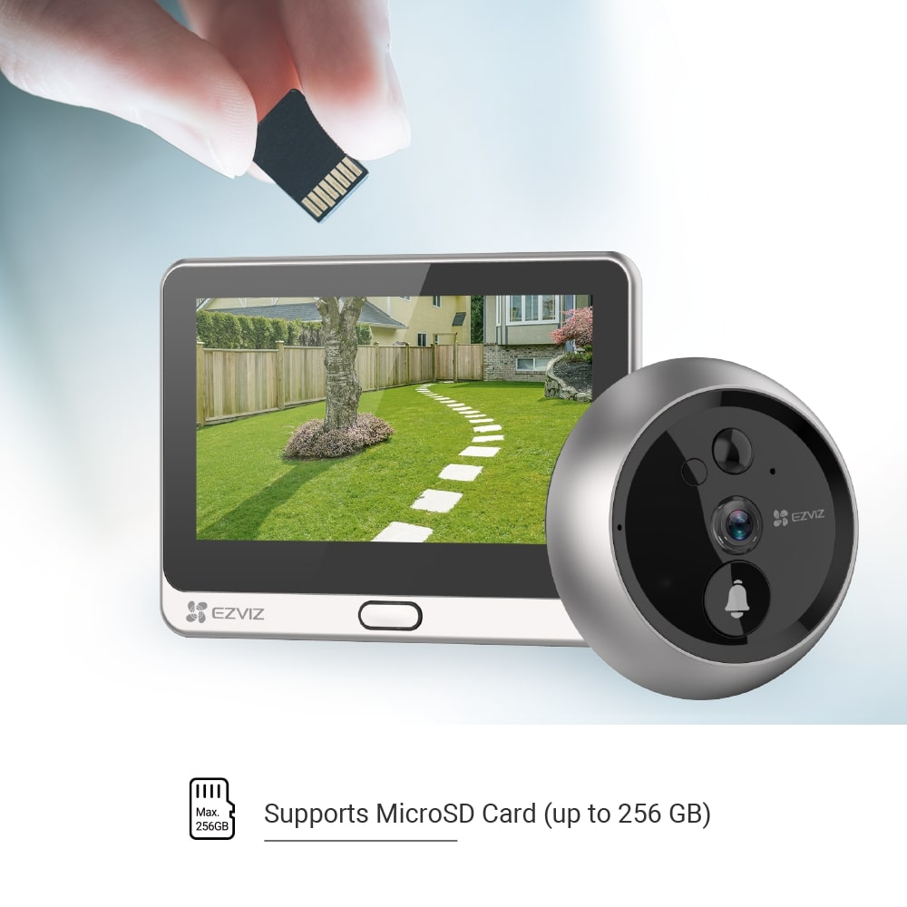 Main tenant une carte microSD au-dessus d'un écran de caméra de sécurité montrant un jardin. Caméra à droite.