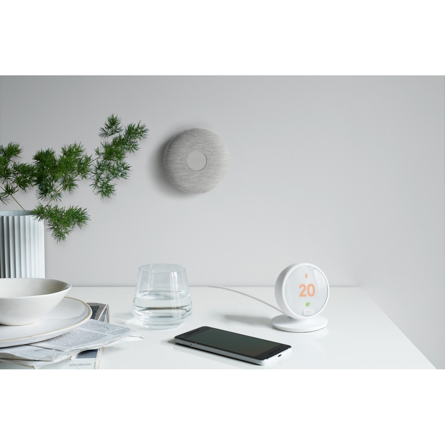 Mesa blanca con dispositivos domésticos inteligentes. Termostato de pared y teléfono.
