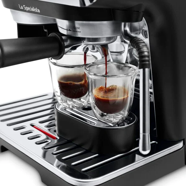 Machine à expresso avec deux verres versant du café. La machine est noire et argentée.