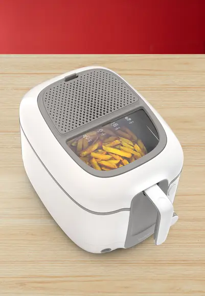 Witte en grijze friteuse met een mandje gouden frietjes erin, op een houten oppervlak.