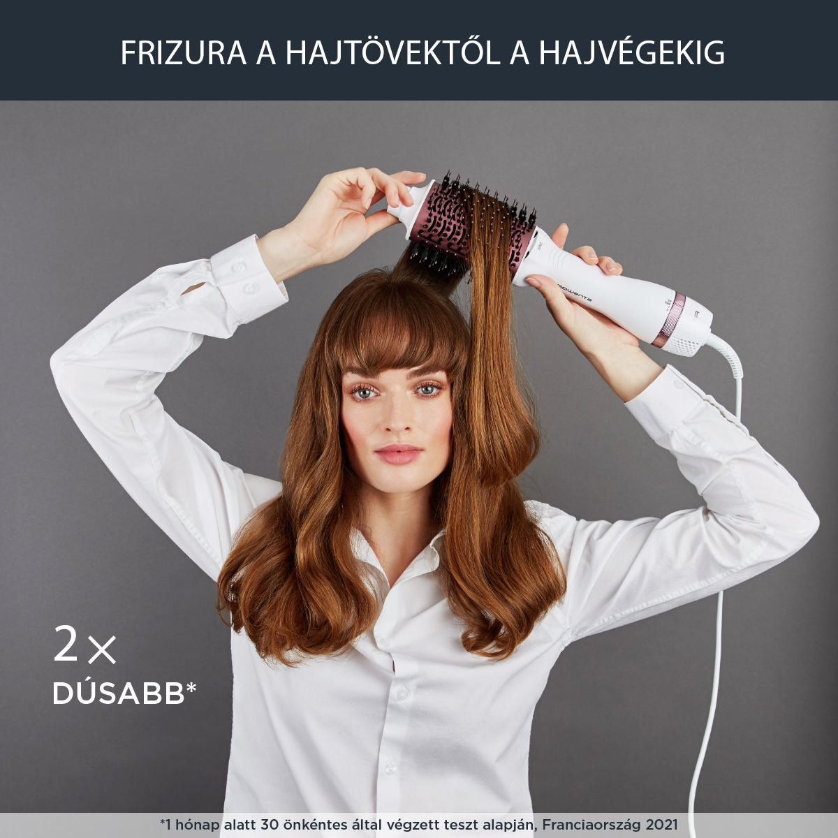 Egy nő piros haját fehér és rózsaszín hajformázó kefével formázza.