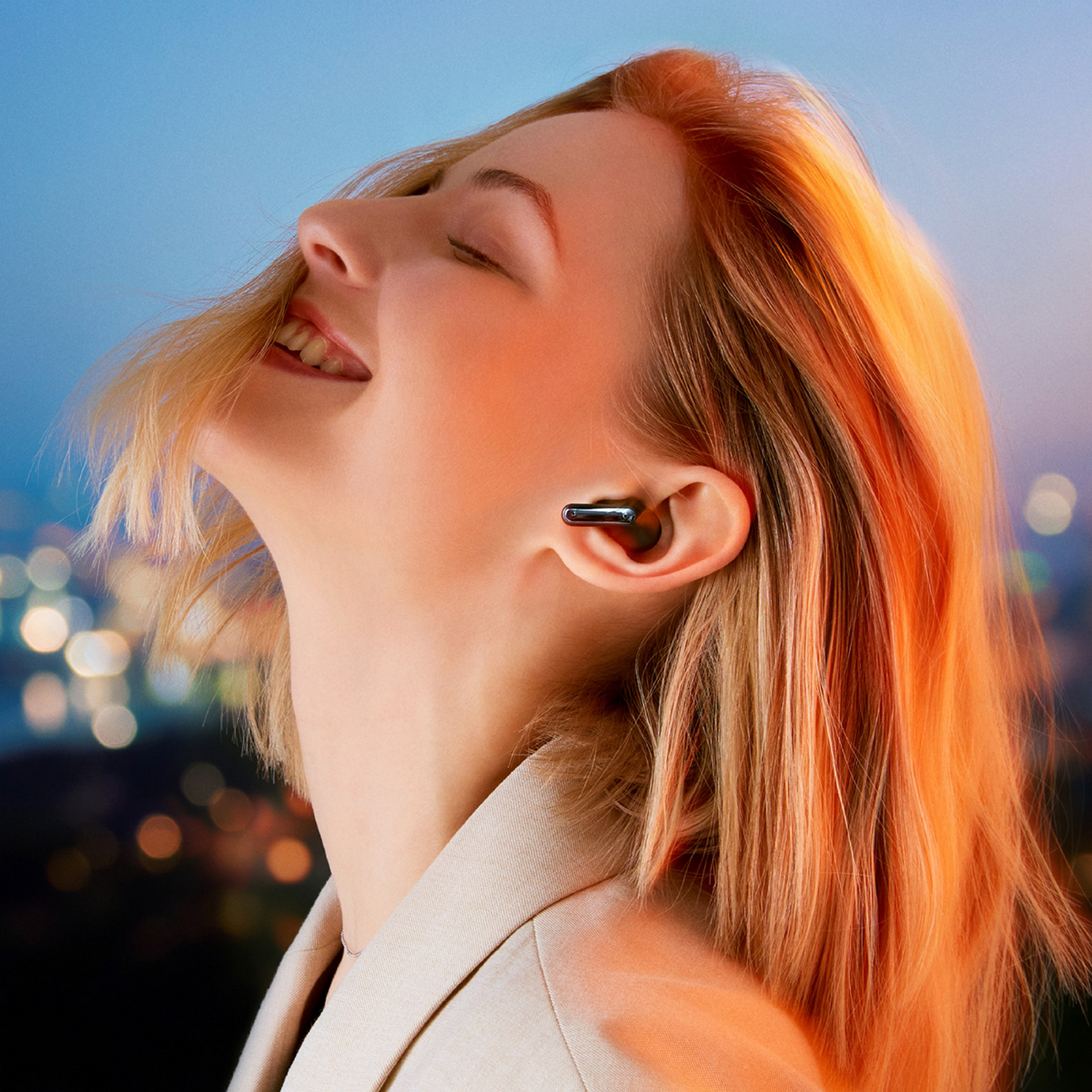 Una mujer pelirroja lleva auriculares. Sonríe con la cabeza inclinada hacia atrás.