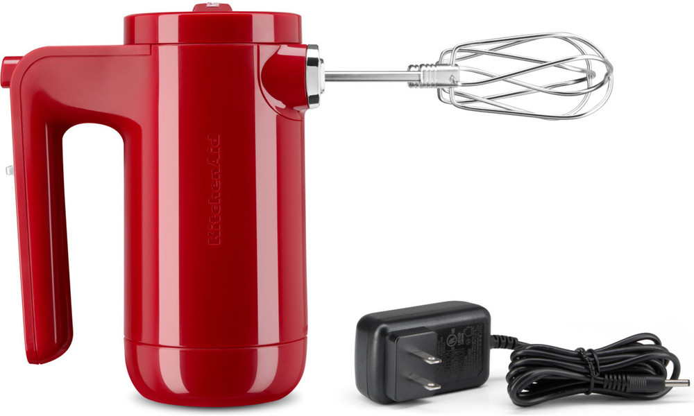 Red KitchenAid hand mixer with a charging cord and adapter.