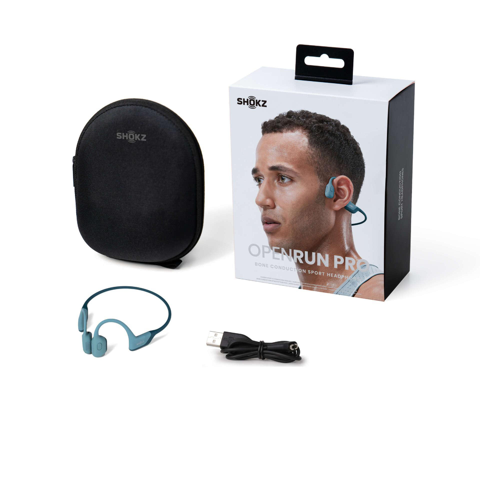Das Bild zeigt Shokz OpenRun Pro Kopfhörer, Etui, Box und Kabel. Die Box zeigt einen Mann mit Kopfhörern.
