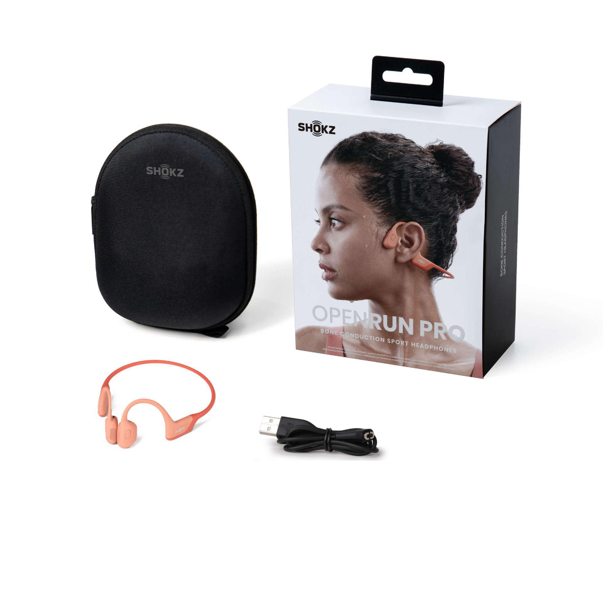 Das Bild zeigt Shokz OpenRun Pro Kopfhörer, eine Hülle und eine Box. Auf der Box ist eine Frau mit Kopfhörern abgebildet. Ein USB-Kabel ist ebenfalls vorhanden.