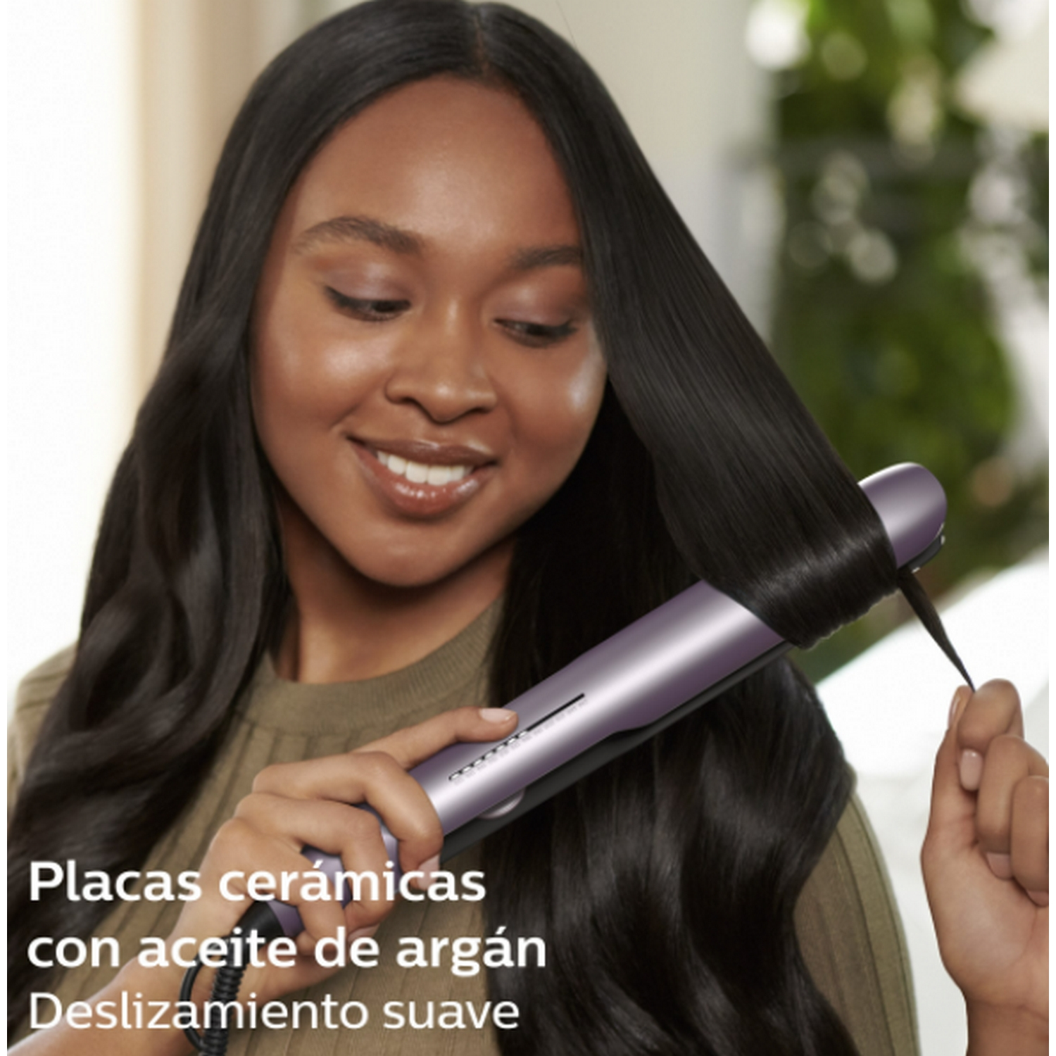 Mujer con cabello largo y oscuro usando una plancha para el cabello. El texto dice 'Placas cerámicas con aceite de argán'.
