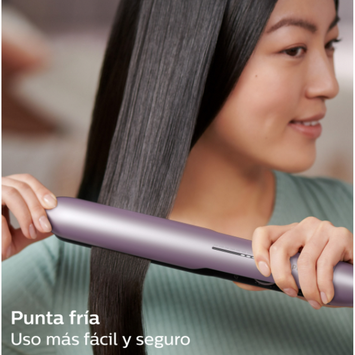 Mujer usando una plancha de pelo morada, primer plano.