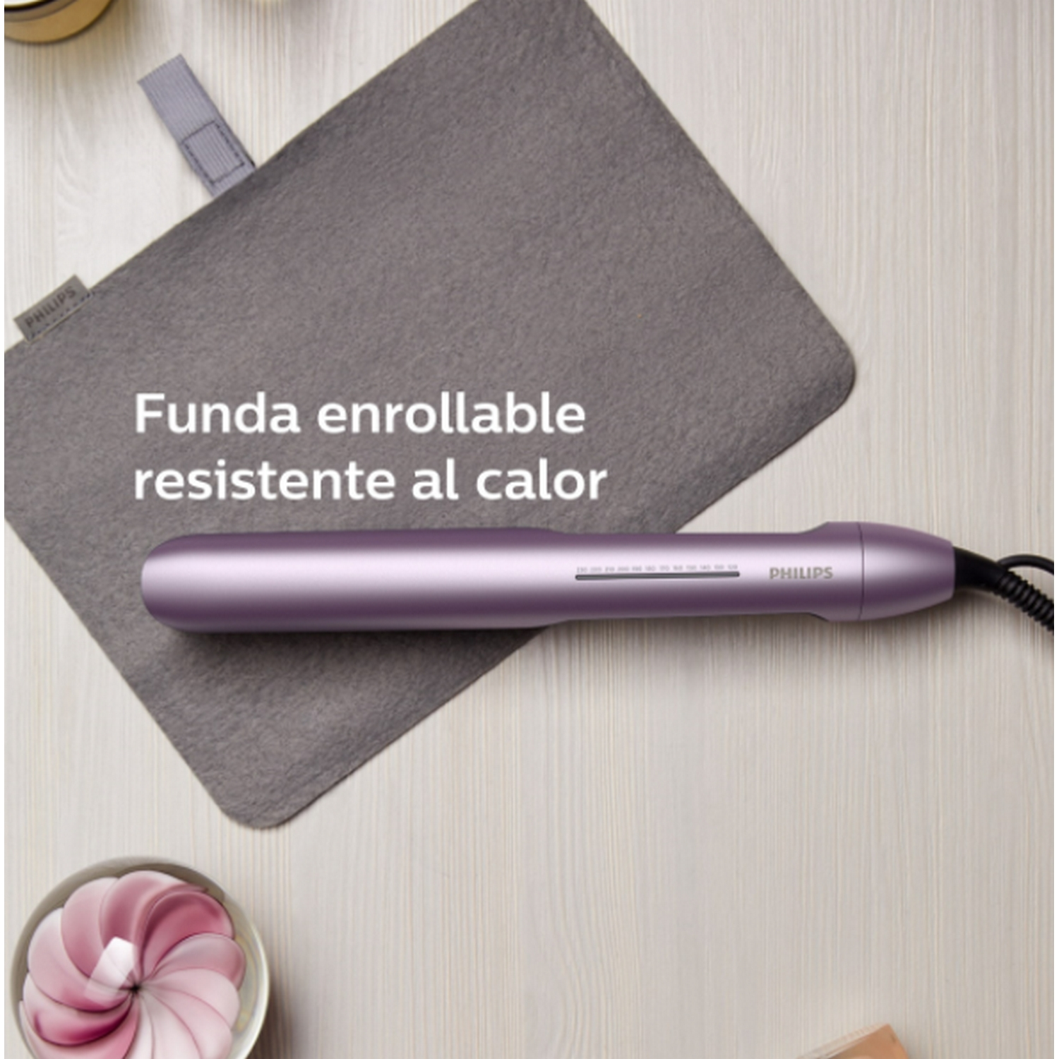 Plancha de pelo morada sobre almohadilla gris con texto. Incluye cable de alimentación.
