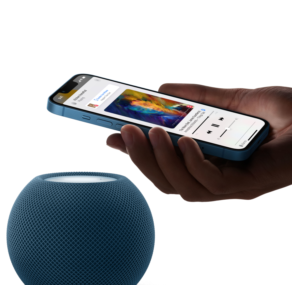 Hand die lichtblauwe iPhone vasthoudt met muziek, met een blauwe speaker ervoor.