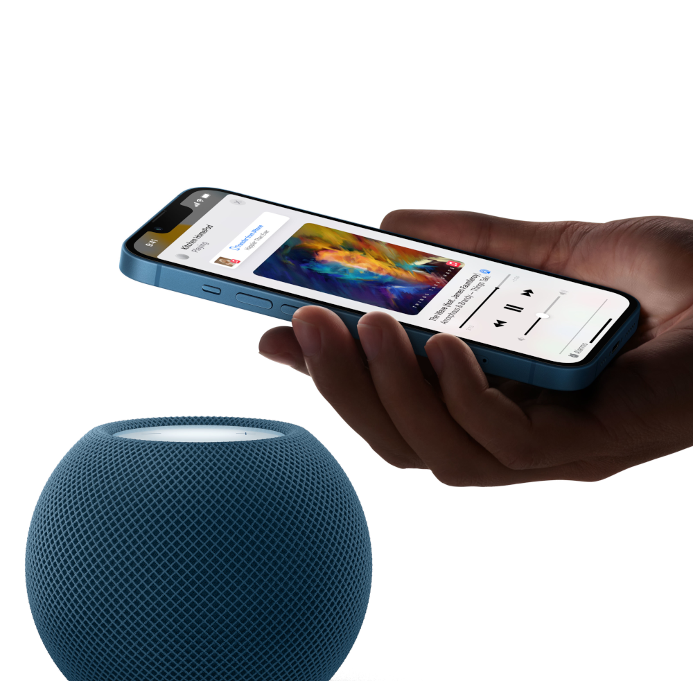 Une main tenant un smartphone bleu à côté d'un haut-parleur sphérique bleu.