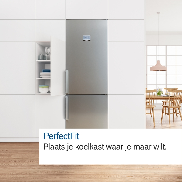 A stainless steel refrigerator in a white kitchen. Cabinets and a dining table are also visible.
