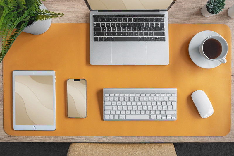 Draufsicht auf einen Schreibtisch. Laptop, Tablet, Telefon, Tastatur, Maus und eine Tasse Kaffee.