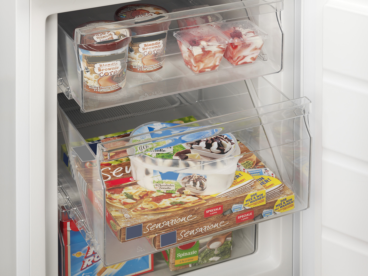 Refrigerator interior with frozen food items in clear plastic drawers.