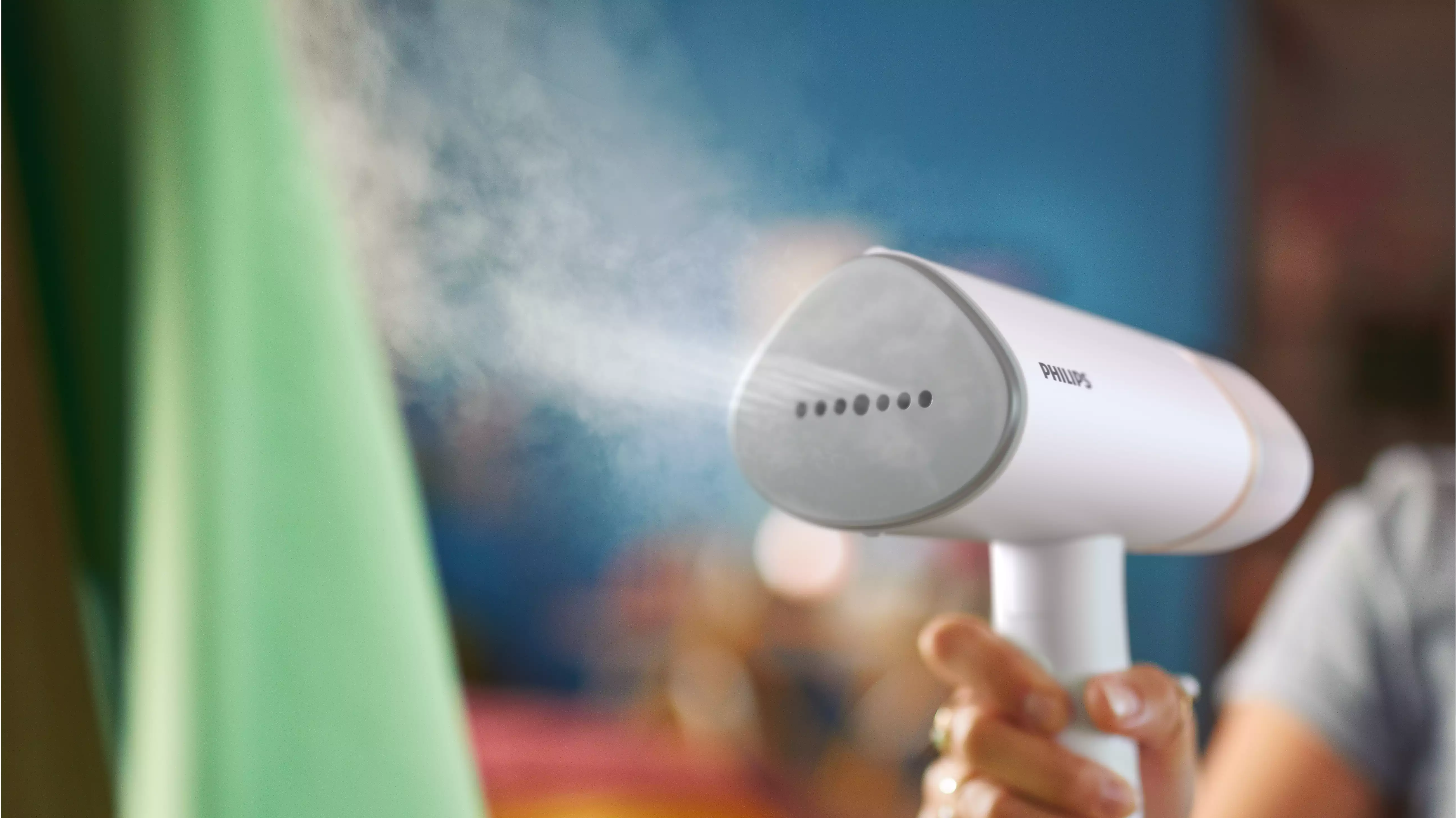 Un défroisseur Philips blanc et gris émettant de la vapeur. L'appareil est tenu par une main.